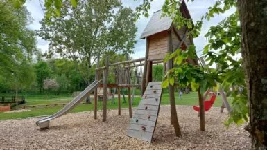 Aire de jeux en bois avec toboggan et structure d'escalade à la motte féodale à Val d'Anast