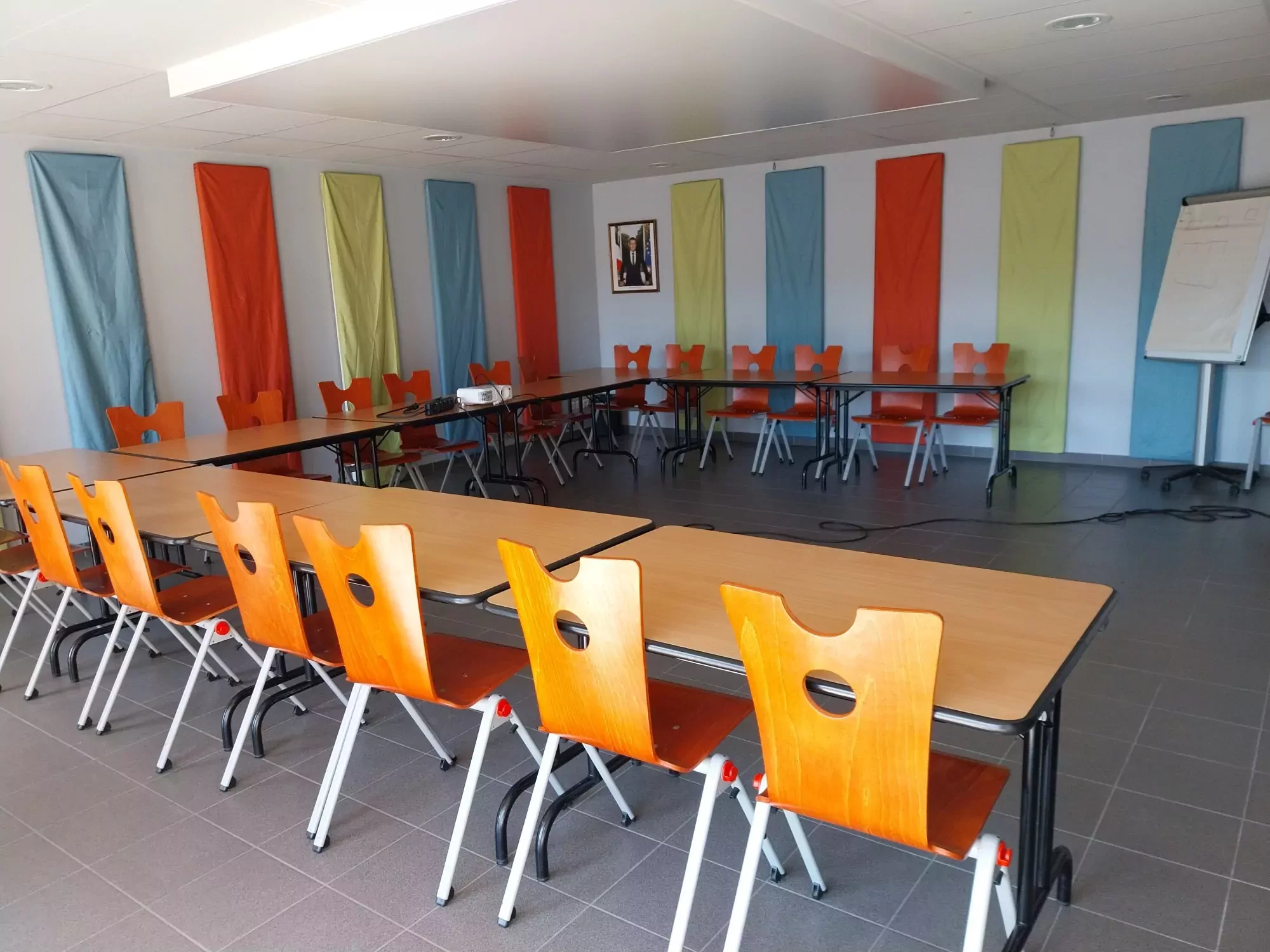 La Salle Jean Marsollier est disponible à la location pour les particuliers, professionnels et associations. Lumineuse, elle accueille les cérémonies comme les réunions. Elle bénéficie de nombreux espaces complémentaires réservables : hall d'accueil, bar et cuisines. Sur cette photo se trouve la salle disposée pour une réunion. Prendre contact avec le Pôle Evénementiel via le formulaire de pré-réservation des salles communales.