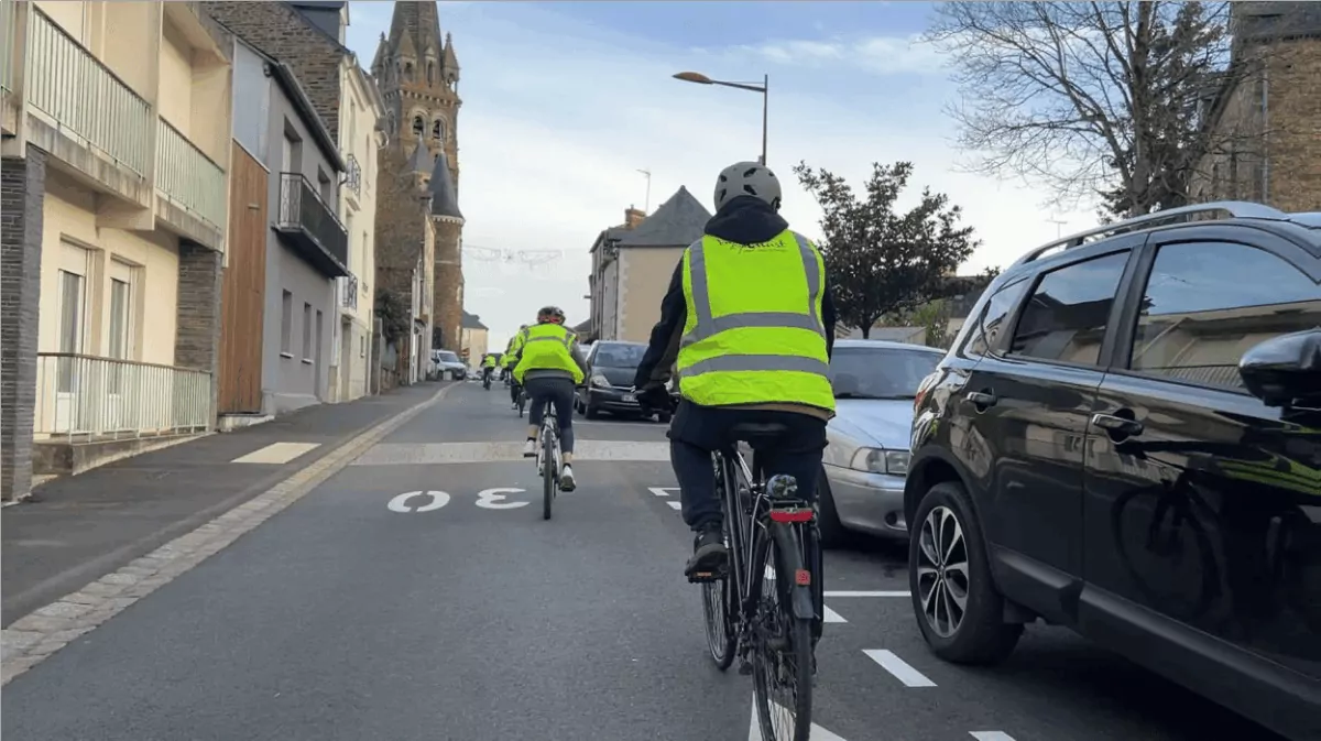 Cyclistes circulant à vélo sur la rue de Guer en direction de l'église de Maure-de-Bretagne à Val d'Anast.