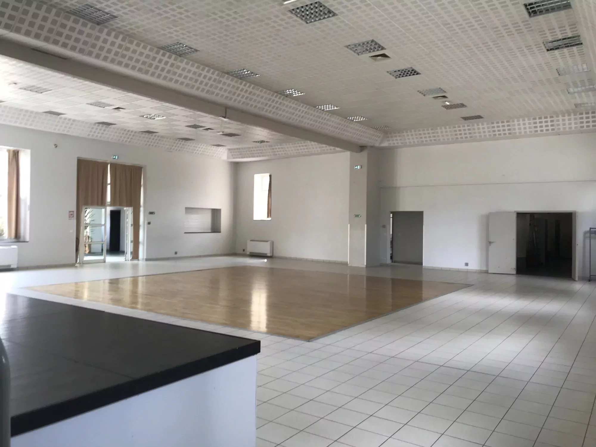 La salle polyvalente de Campel est disponible à la location pour les particuliers, professionnels et associations. Dans le cœur du bourg de Campel, elle est équipée d'un parquet, d'une scène, d'un bar. Sur cette photo se trouve la salle vue de la scène. Prenez contact avec le Pôle Événementiel via le formulaire de pré-réservation en ligne.