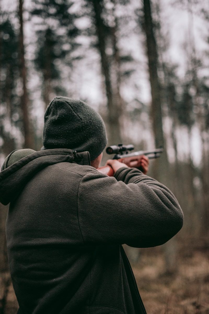 Chasseur pointant son fusil en direction de la forêt