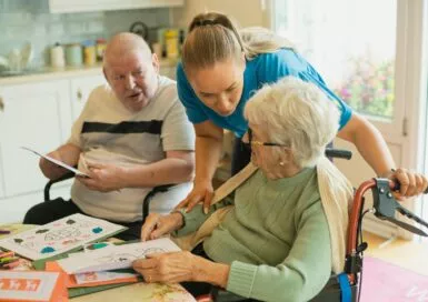Aide-soignante accompagnant un couple de senior lors d'une activité créative.