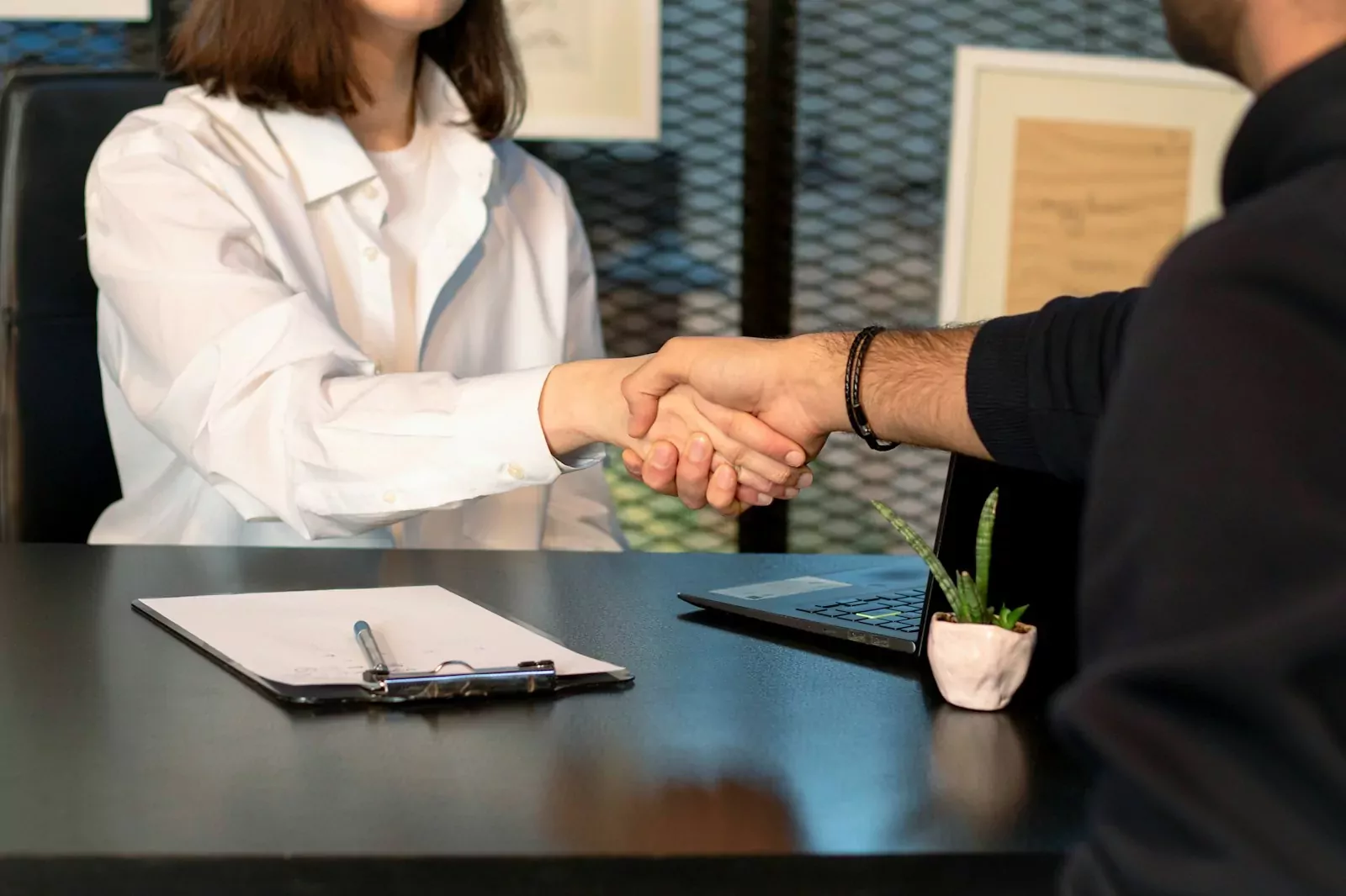 Un homme et une femme effectuent une poignée de main après la signature d'un contrat de travail.